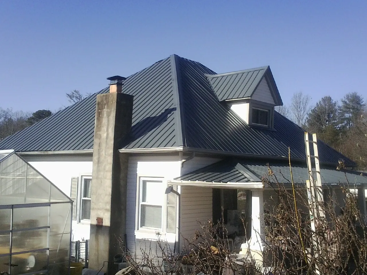 Dark blue standing seam metal roof on a white farmhouse with dormer — Slate & Tile Roof Repair by Roofing Brothers in Woodridge