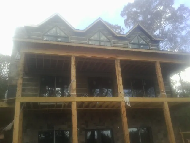 Dormers and porch framing on a large log home under construction — Roof Coating work by our crew in Woodridge